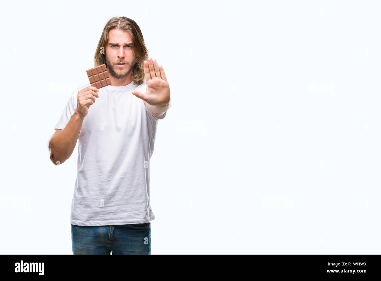 Junger stattlicher Mann mit langen Haaren Schokolade essen Bar über isolierte Hintergrund mit der offenen Hand tun, STOP-Schild mit ernsten und selbstbewussten Ausdruck, Stockfoto