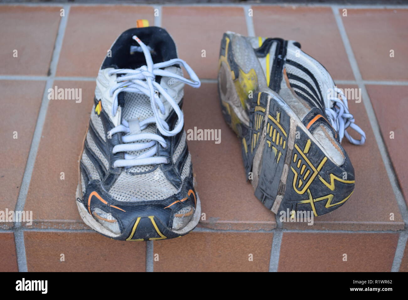 Paar alte Laufen und Laufschuhe und mit Bohrungen unter der alleinigen getragen. Paar alte Lauf- und Wanderschuhe und abgenutzt, mit Löchern unter der Sohle Stockfoto