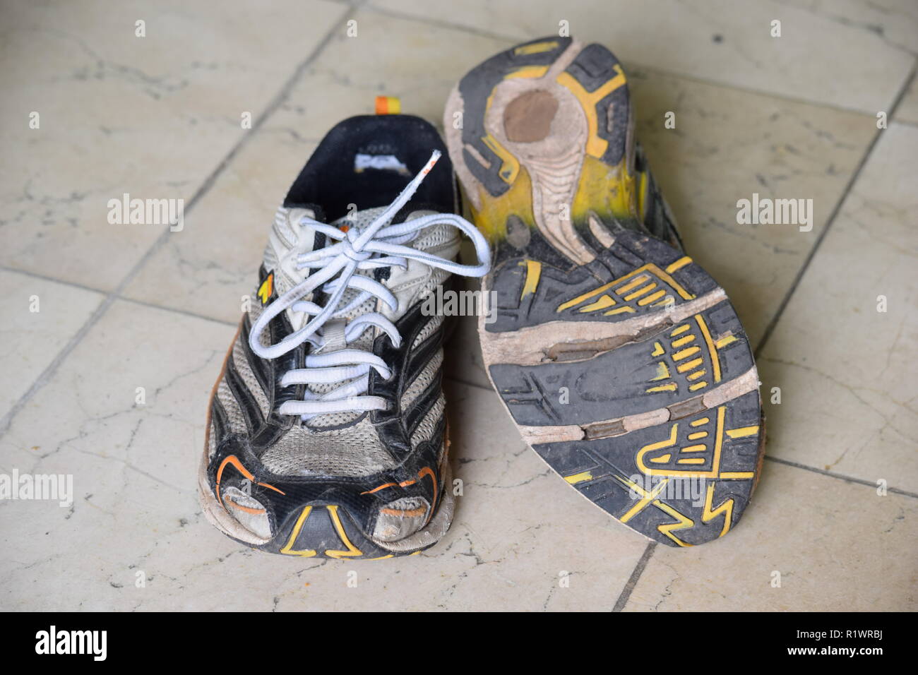 Paar alte Laufen und Laufschuhe und mit Bohrungen unter der alleinigen getragen. Paar alte Lauf- und Wanderschuhe und abgenutzt, mit Löchern unter der Sohle Stockfoto