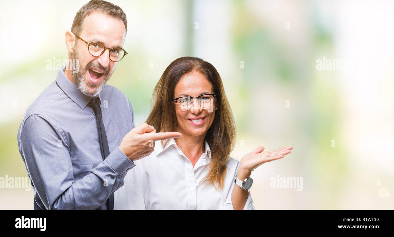 Mittleres Alter spanischer verliebtes Paar Brillen über isolierte Hintergrund erstaunt und lächelt in die Kamera während der Präsentation und mit der Hand nach w Stockfoto