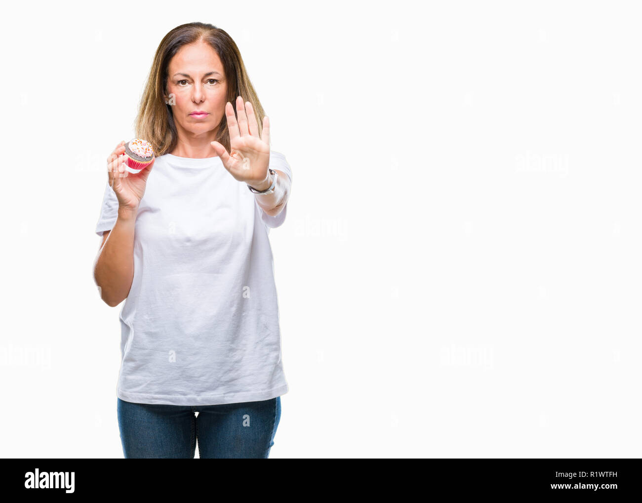 Mittleres Alter Hispanic Frau essen Cupcake über isolierte Hintergrund mit der offenen Hand tun, STOP-Schild mit ernsten und selbstbewussten Ausdruck, Verteidigung gestur Stockfoto