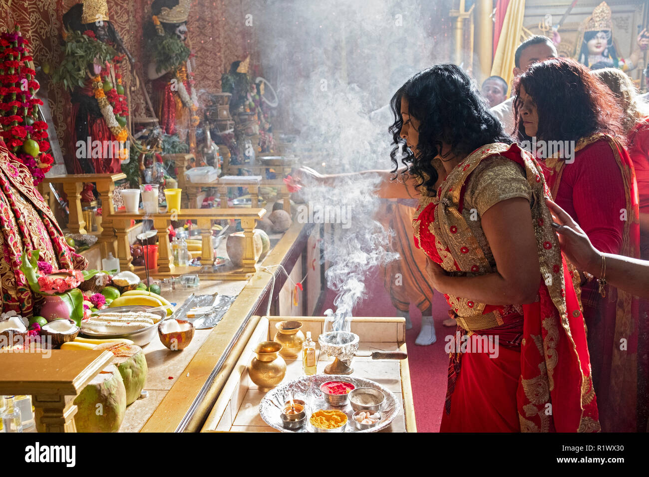 Eine weibliche Hindu devotee verbrennt Weihrauch vor der Göttin Kali an einem Shakti Hindutempel in Queens, New York City. Stockfoto