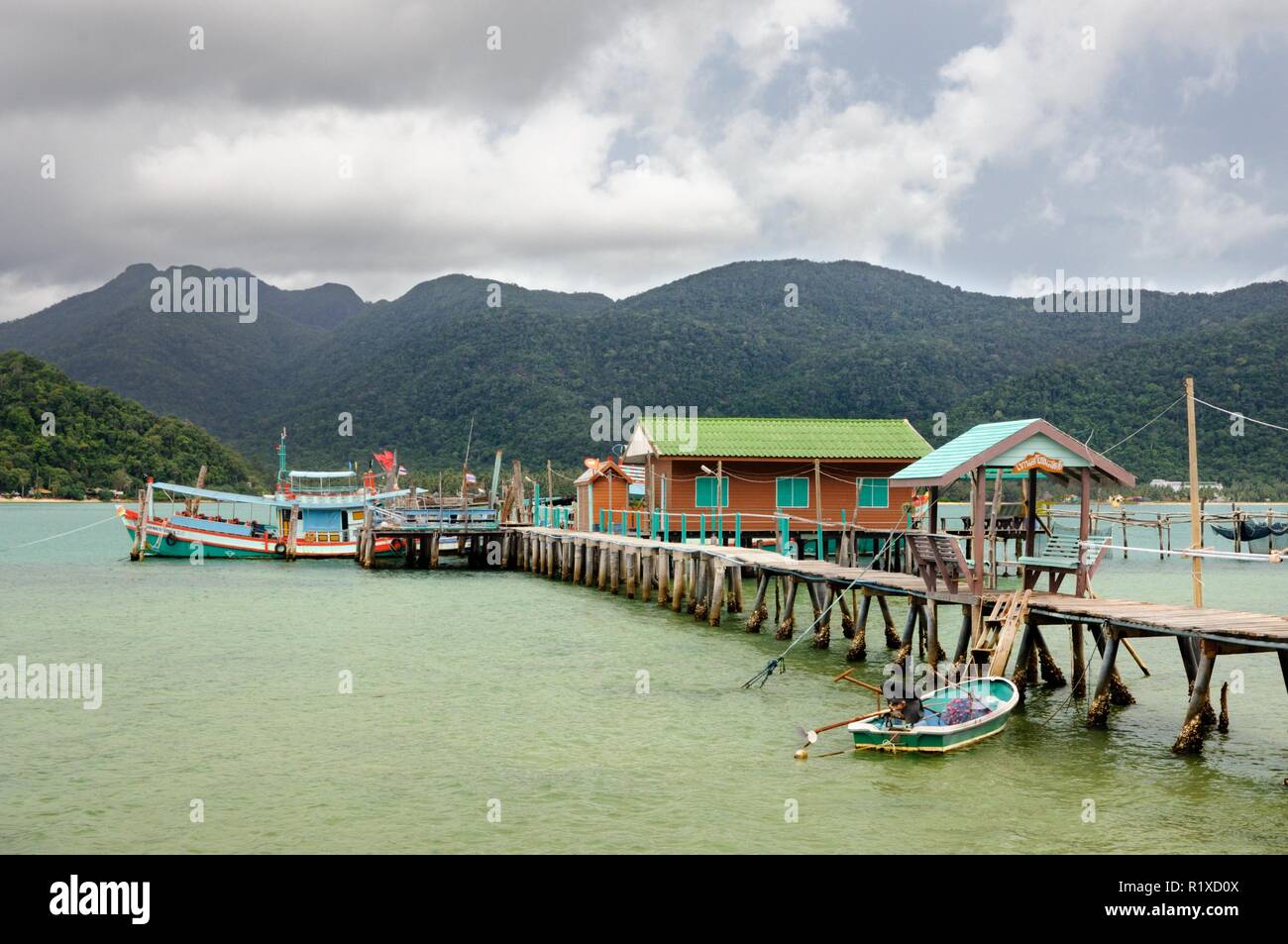 Tropische Landschaft mit Türkis tropischen Meer, Angeln, Boot, Haus auf dem Wasser, Holz- pier und tropischen Koh Chang Insel am Horizont in Thailand Stockfoto