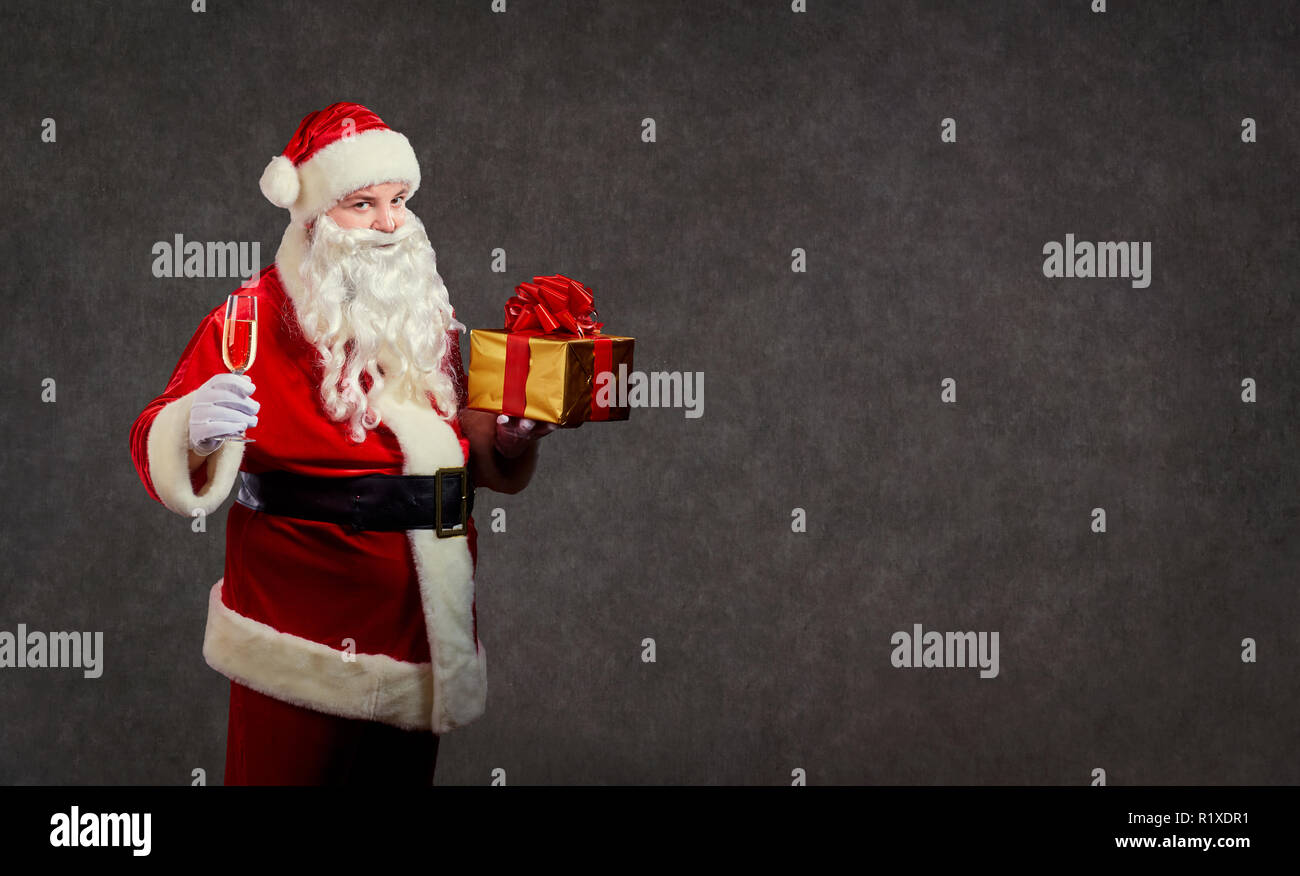 Santa Claus mit einem Geschenk und einem Glas Champagner. Stockfoto
