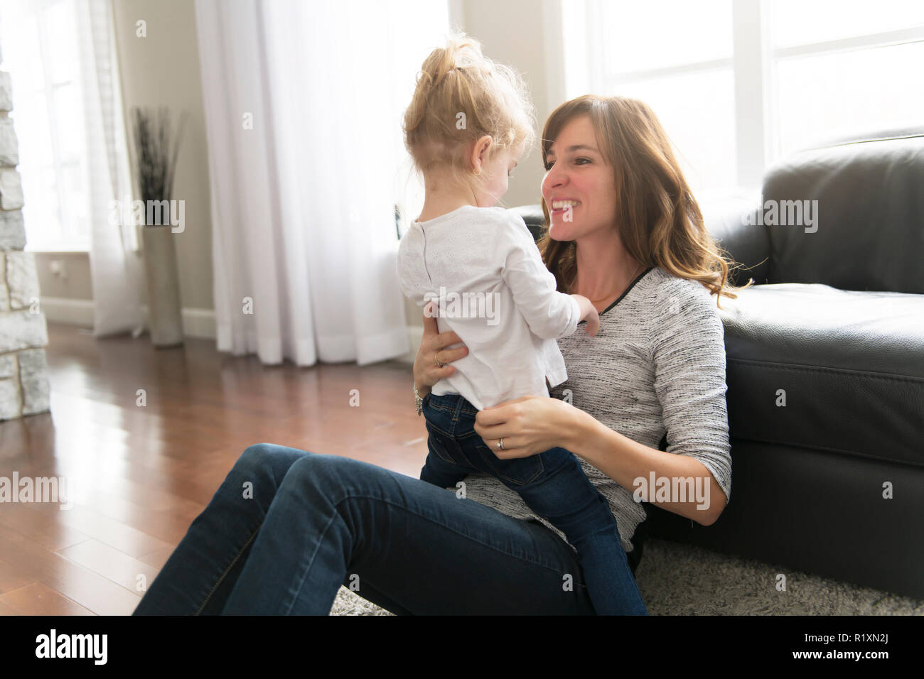 Eine glückliche Mutter mit ihrer kleinen Tochter im Wohnzimmer zu Hause. Stockfoto