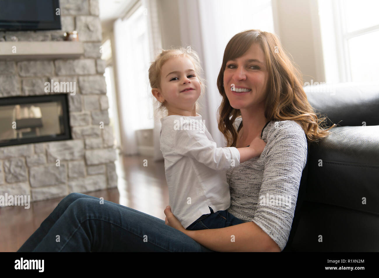 Eine glückliche Mutter mit ihrer kleinen Tochter im Wohnzimmer zu Hause. Stockfoto