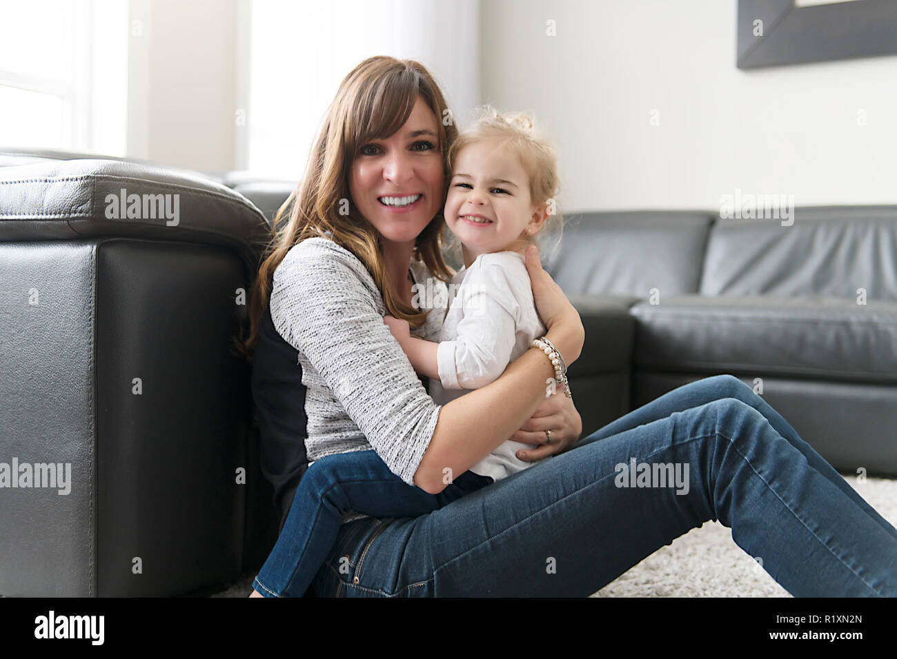 Eine glückliche Mutter mit ihrer kleinen Tochter im Wohnzimmer zu Hause. Stockfoto