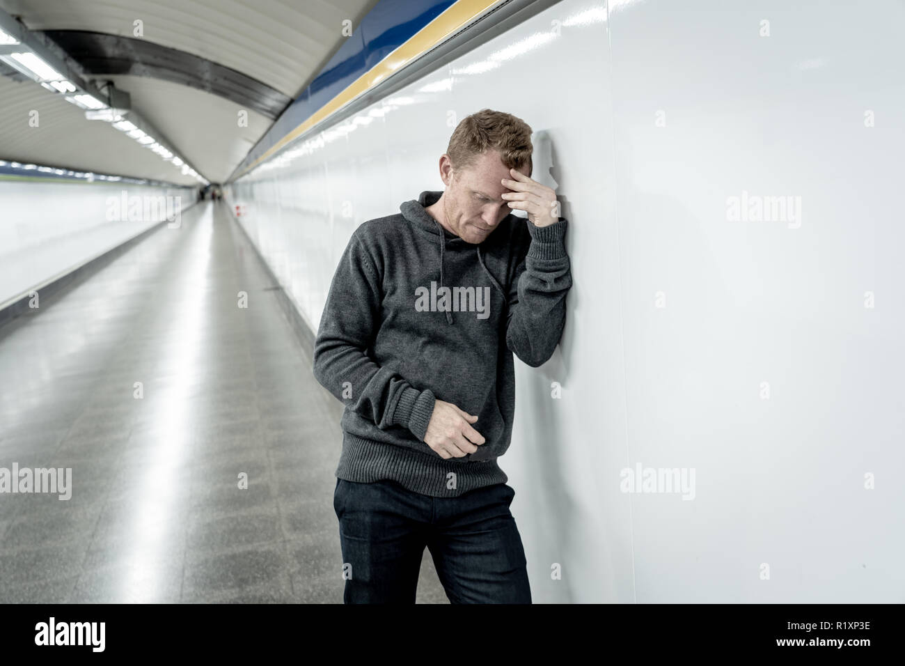 Miserable arbeitslose junge Mann weinen Drogensüchtigen Obdachlosen in Depression stress sitzen auf dem Boden Street U-Bahn Tunnel suchen verzweifelt lehnte sich an der Wand Stockfoto