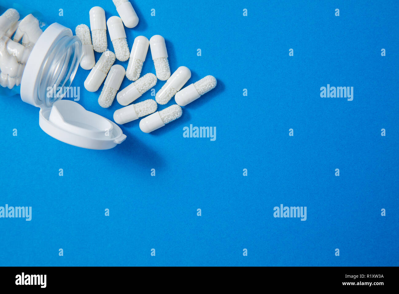 Verschüttete Pillen und jar auf blauem Hintergrund mit Copyspace auf der rechten Seite Stockfoto
