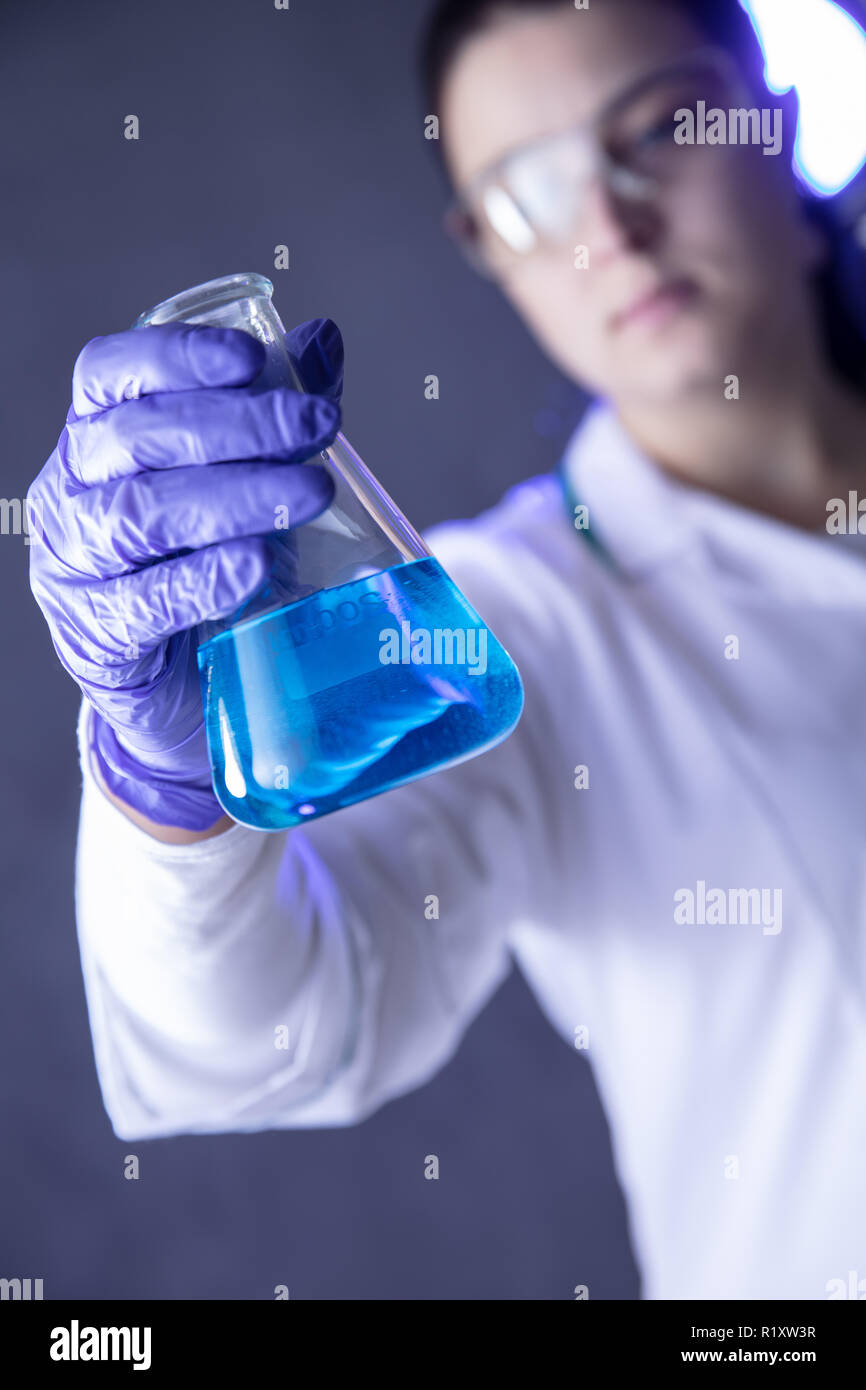Der Chemiker Hand hält Flasche mit blauer Flüssigkeit im Labor. Vertikale Ansicht Stockfoto