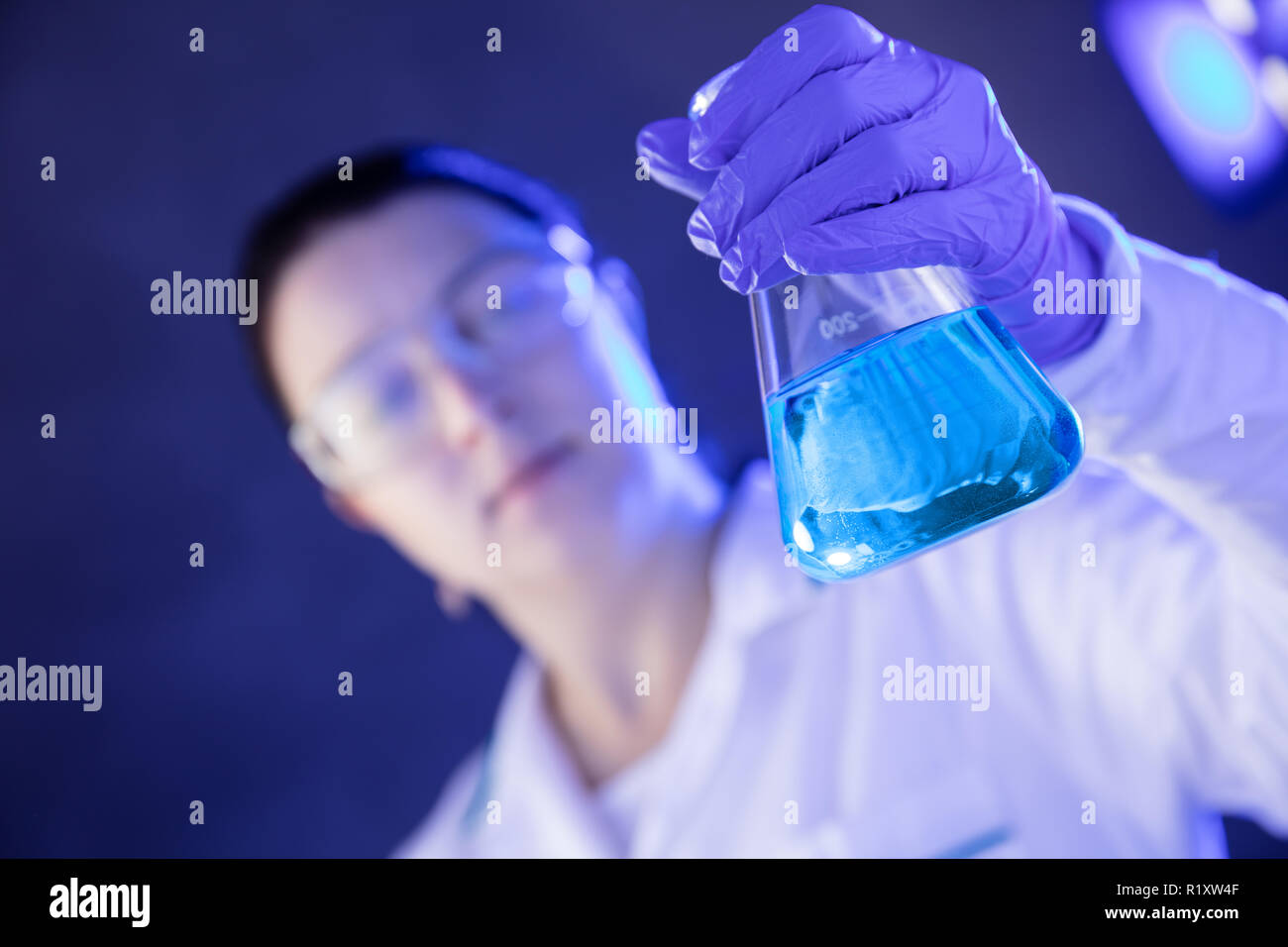 Chemiker im Labor schaut auf blaue Flüssigkeit in der Flasche. Horizontale Ansicht Stockfoto