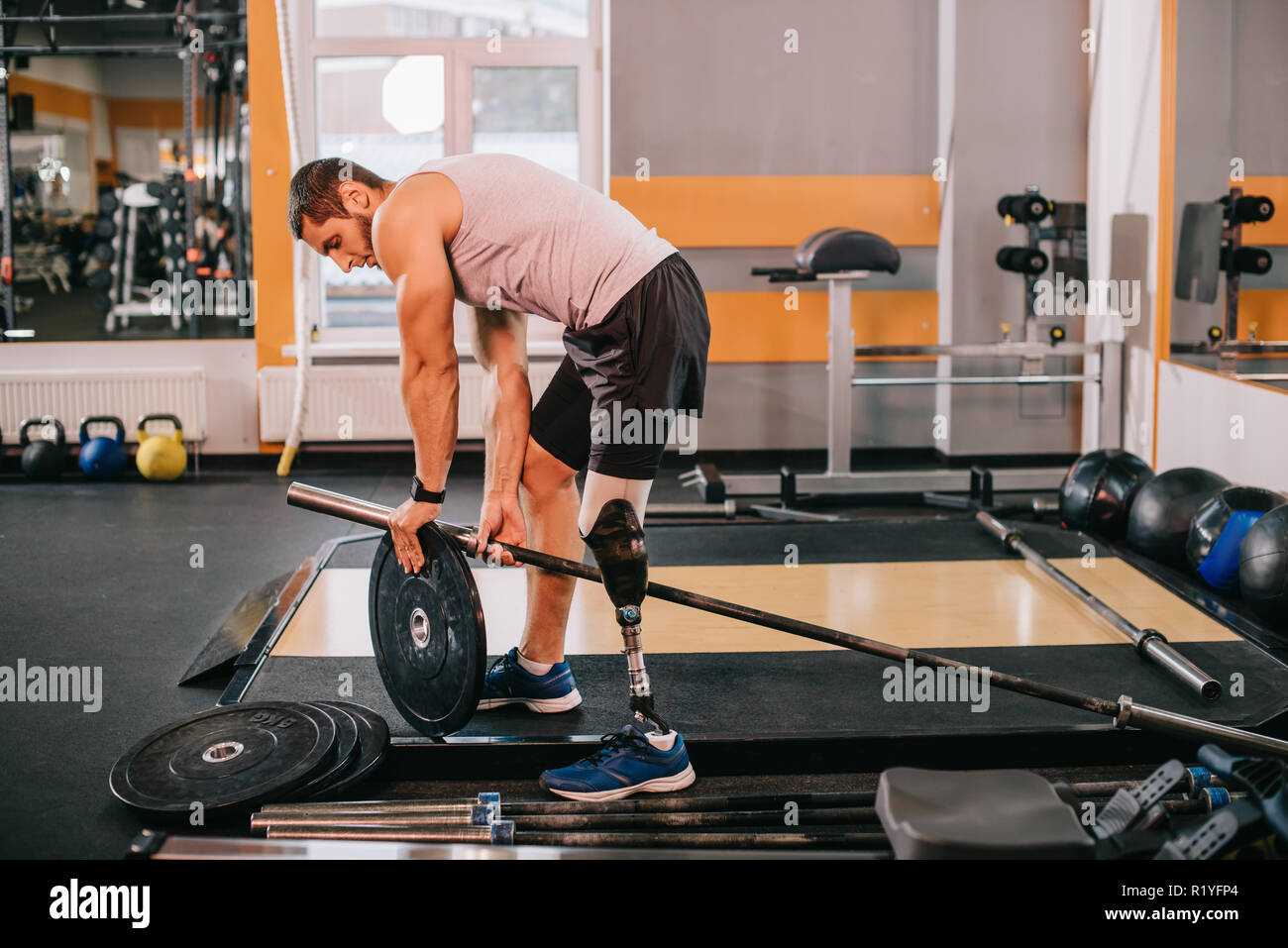 Hübscher junger Sportler mit künstlichen Bein Gewichtszunahme die Platte an der Bar im Fitnessbereich Stockfoto