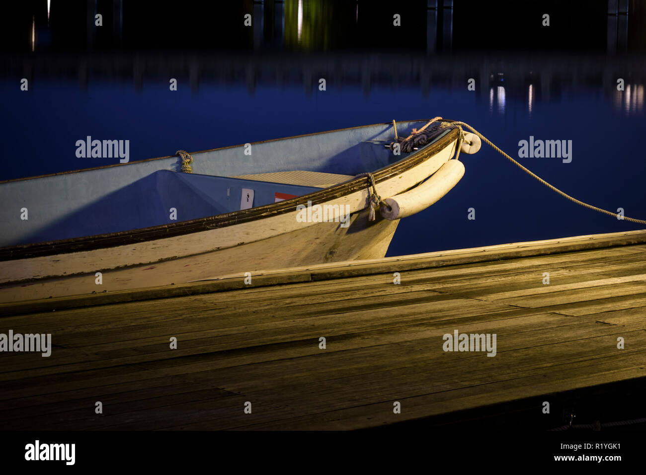 Ein kleines Holzboot am Dock oder Pier in der Nacht geparkt. Nacht der Fotografie mit Blau glatte Wasser. Stockfoto