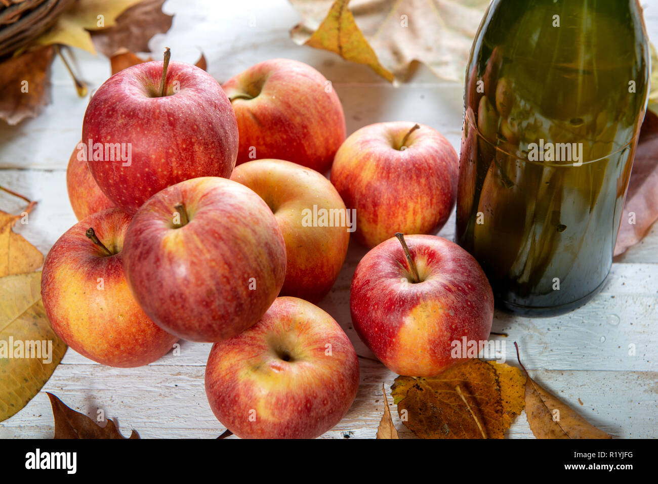 Blätter im Herbst mit einer Flasche Apfelwein und und Äpfel Stockfoto