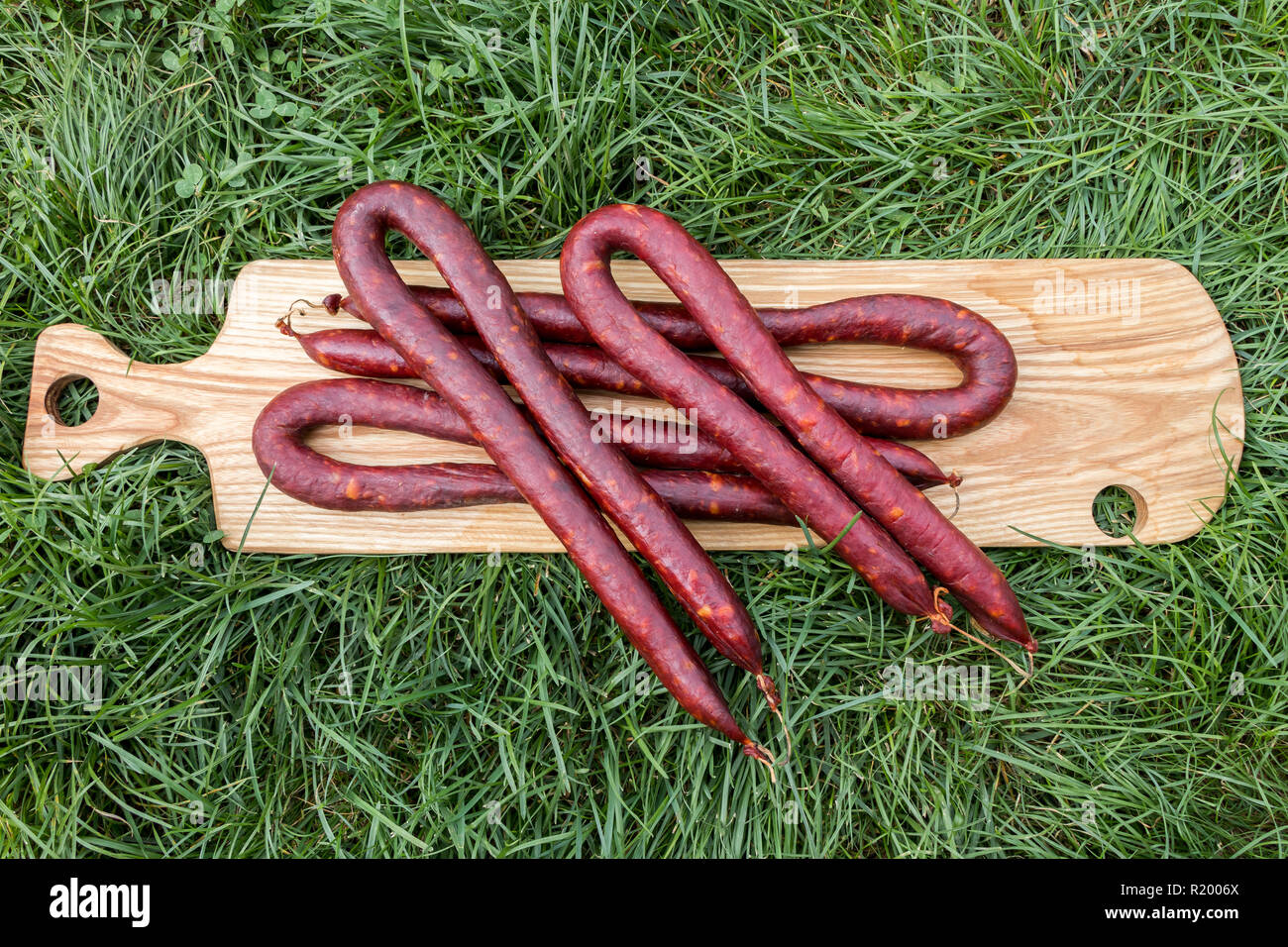 Slowakischen Würstchen aus Schweinefleisch auf einem Holzbrett auf Gras, Serbien Stockfoto