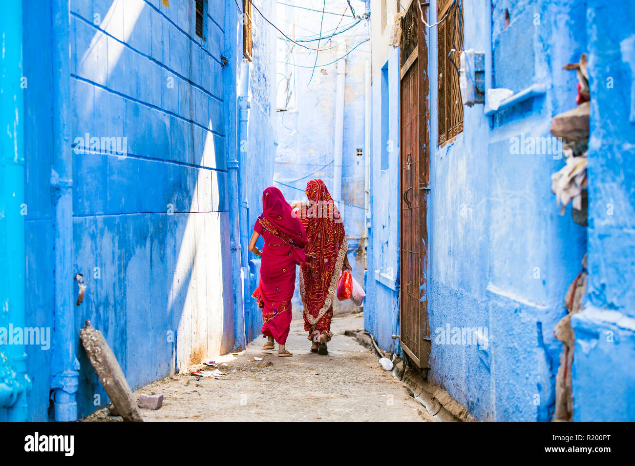 Zwei Frauen in der traditionellen indischen Sari gekleidet sind ein Spaziergang durch die engen Gassen von die blaue Stadt Jodhpur, Rajasthan, Indien. Stockfoto