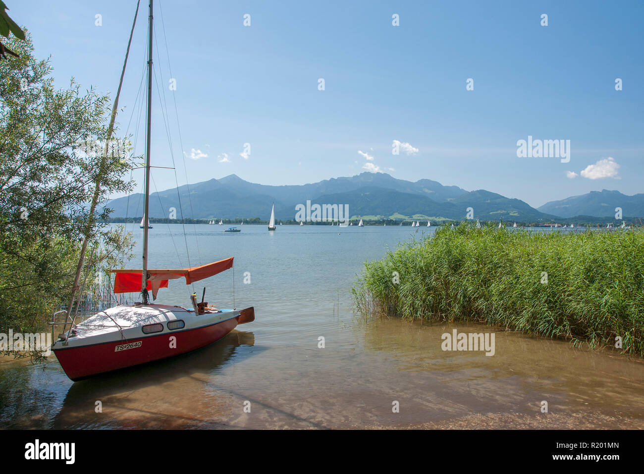 Chiemsee. Segelboot an der Küste mit Insel Herreninsel im Hintergrund, Bayern, Deutschland Stockfoto