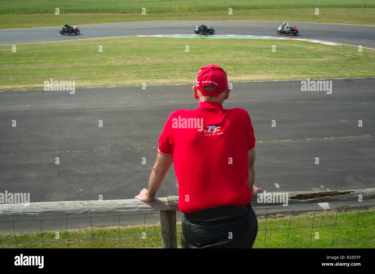 Motorrad Racing Zuschauer einen roten Isle of Man TT Polo Shirt und eine rote Kappe in Castle Combe, Wiltshire Stockfoto