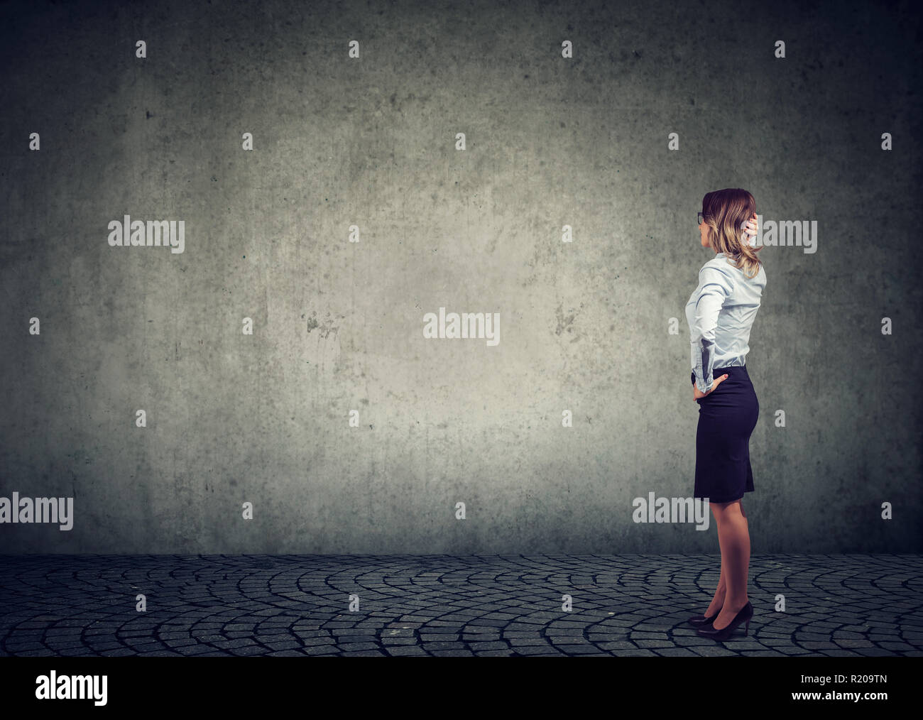 Ansicht der Rückseite des Business woman von der Wand mit der Hand auf den Kopf, was dann zu tun ist angefochten wird. Volle Länge des Geschäftsfrau mit Blick auf den Stockfoto