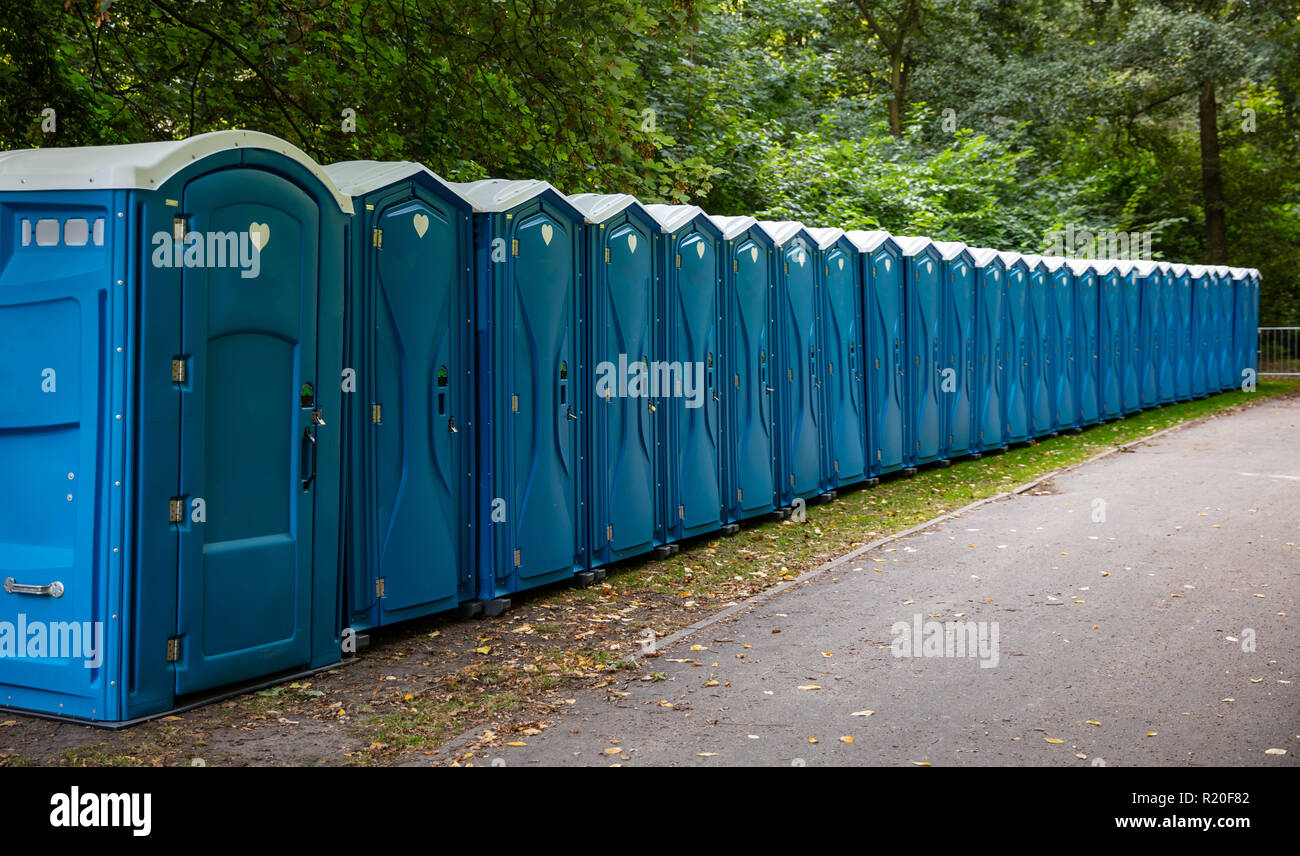 Mobile WC-Kabinen im Park. Eine Linie von chemischen Toiletten für ein Festival, gegen einen Wald Hintergrund Stockfoto