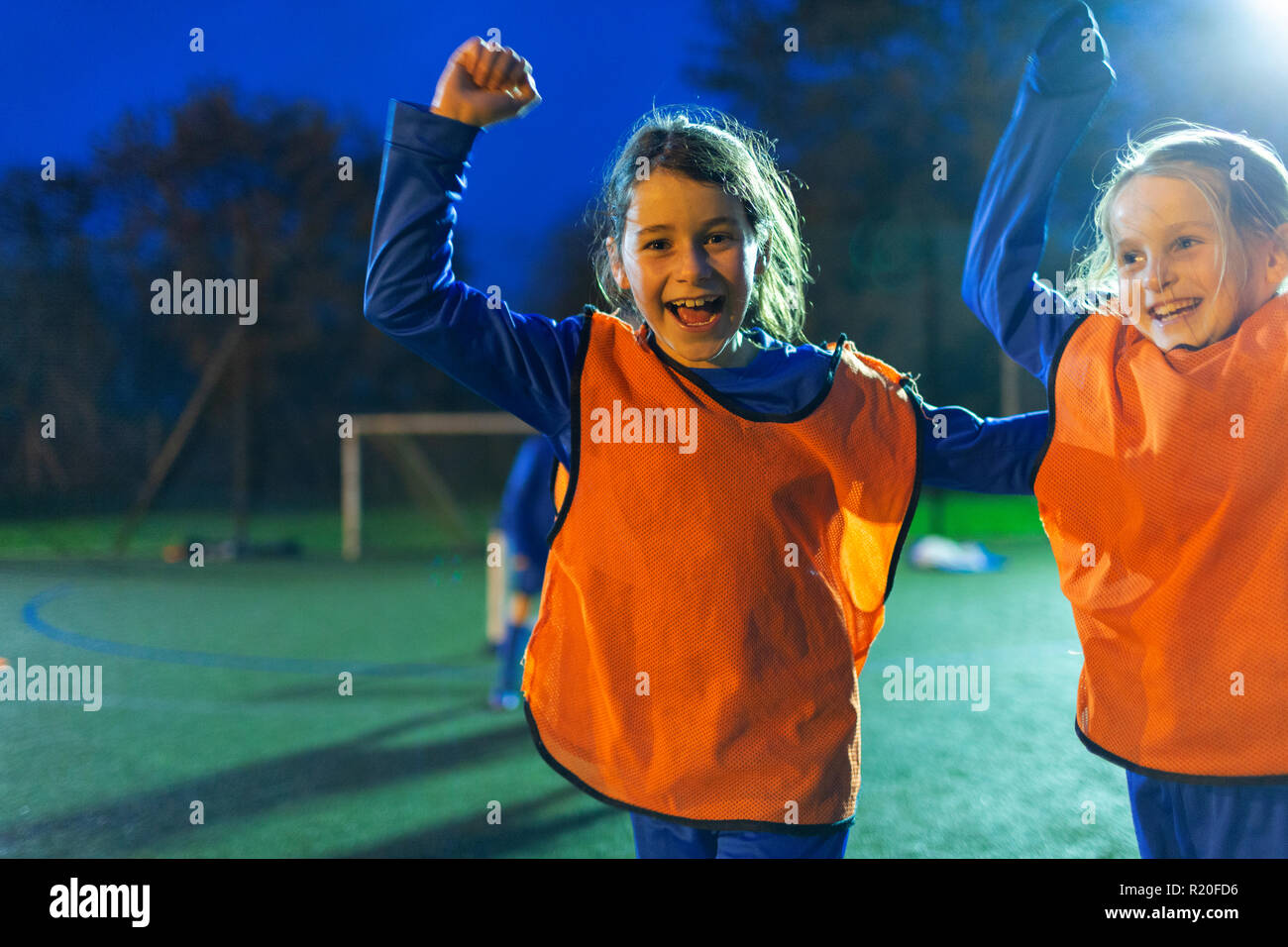 Portrait begeisterte Mädchen Fußball-Spieler jubelnd auf Feld bei Nacht Stockfoto