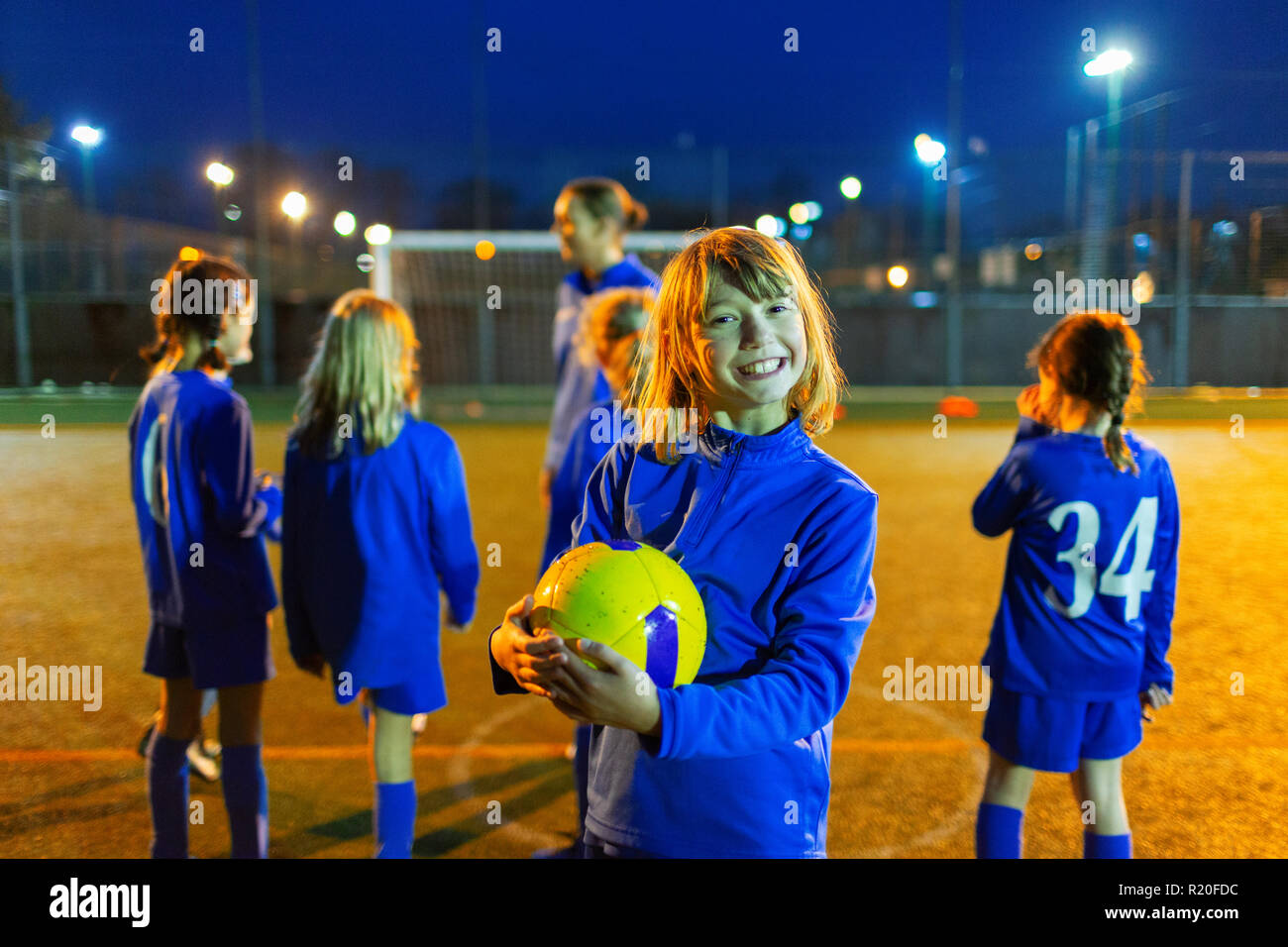 Porträt Lächeln, begeisterte Mädchen mit Fußball-Praxis auf dem Feld in der Nacht Stockfoto
