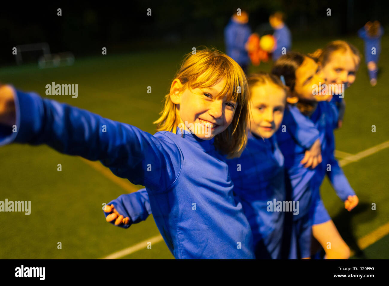 Porträt Lächeln, selbstbewusste Mädchen Fußball Team auf dem Feld in der Nacht Stockfoto