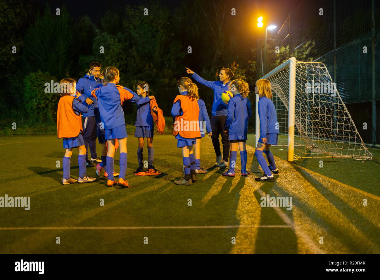 Mädchen Fußball Team hören Trainer auf Feld bei Nacht Stockfoto