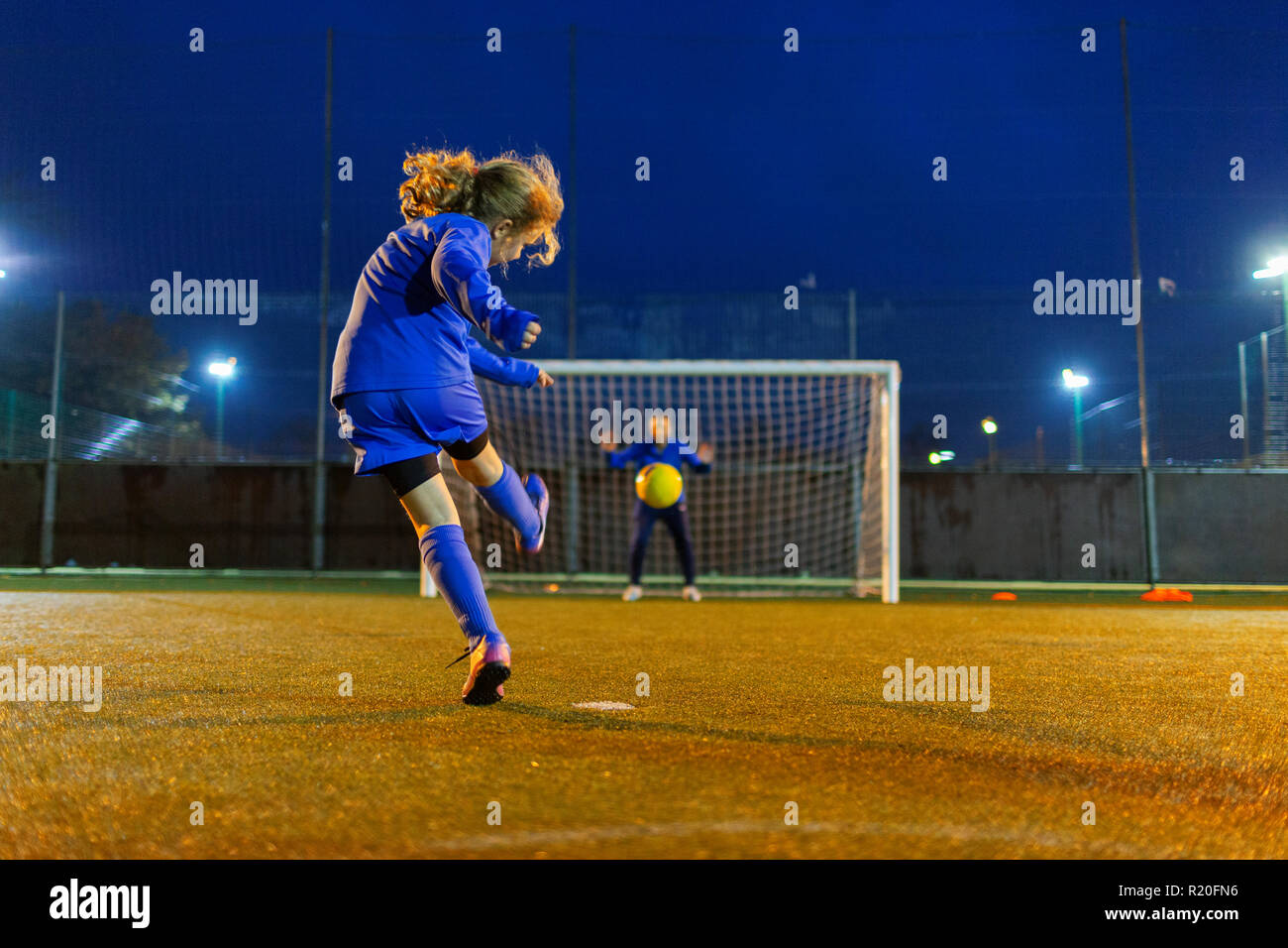 Mädchen Fußball-Spieler kicken den Ball Richtung Tor Stockfoto