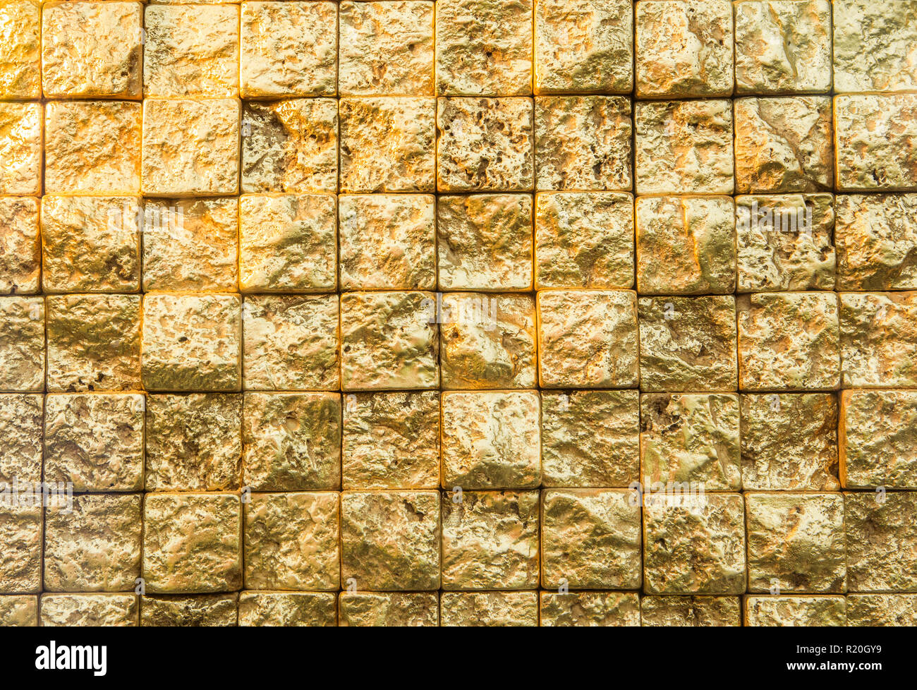 Holprige golden klein, sogar Plätze Mauer Hintergrund. Stockfoto