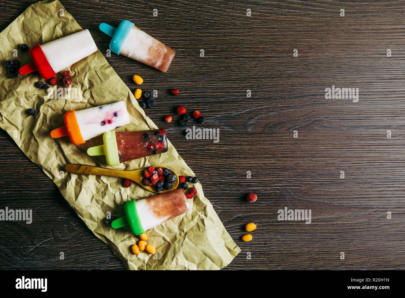 Flach Blick auf viele hausgemachte Kühlschrank frozen Smoothie Joghurt Saft Eis mit Beeren auf dunklen dramatische Holz- Hintergrund. Gesunde snack c Stockfoto