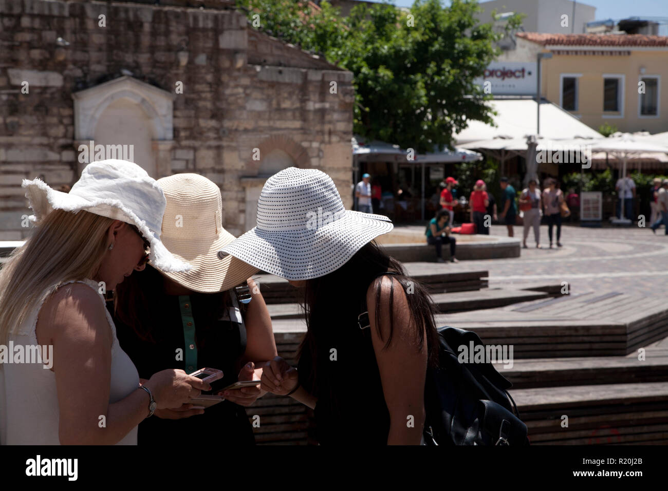 Drei junge Frauen mit weißen Sonne Hüte bei Handys plateia Monastiraki, Athen, Griechenland Stockfoto