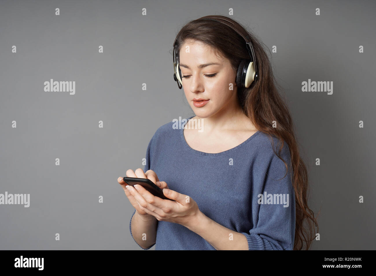 Junge Frau hört Musik mit kabellosen bluetooth-Kopfhörern und mobilen Smartphones Stockfoto