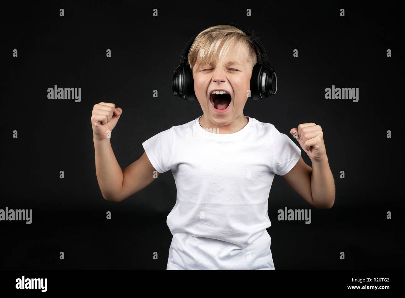 Kleine blonde Junge schreit laut mit einem Kopfhörer Stockfoto