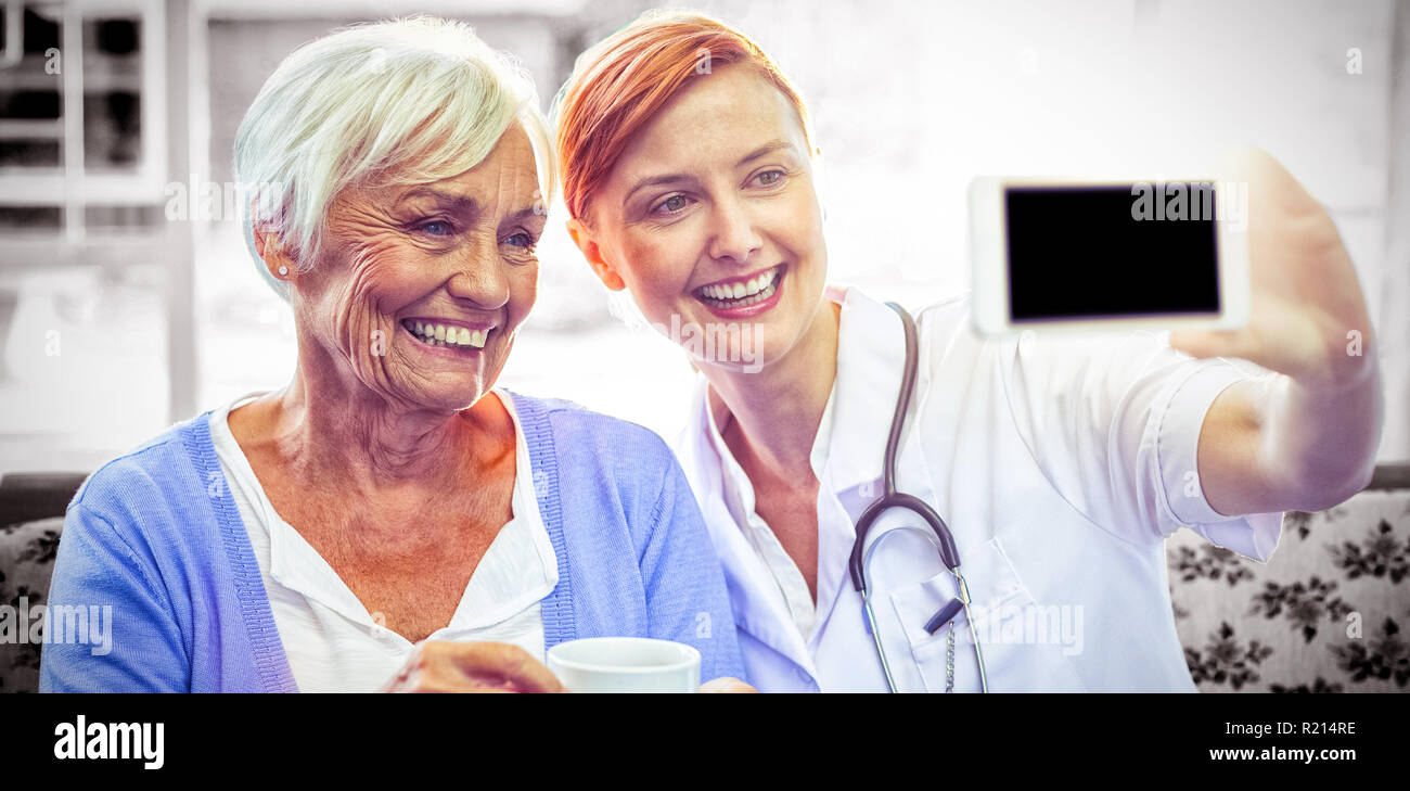 Lächelnd, Arzt und Patienten betrachten Telefon beim Tee Stockfoto