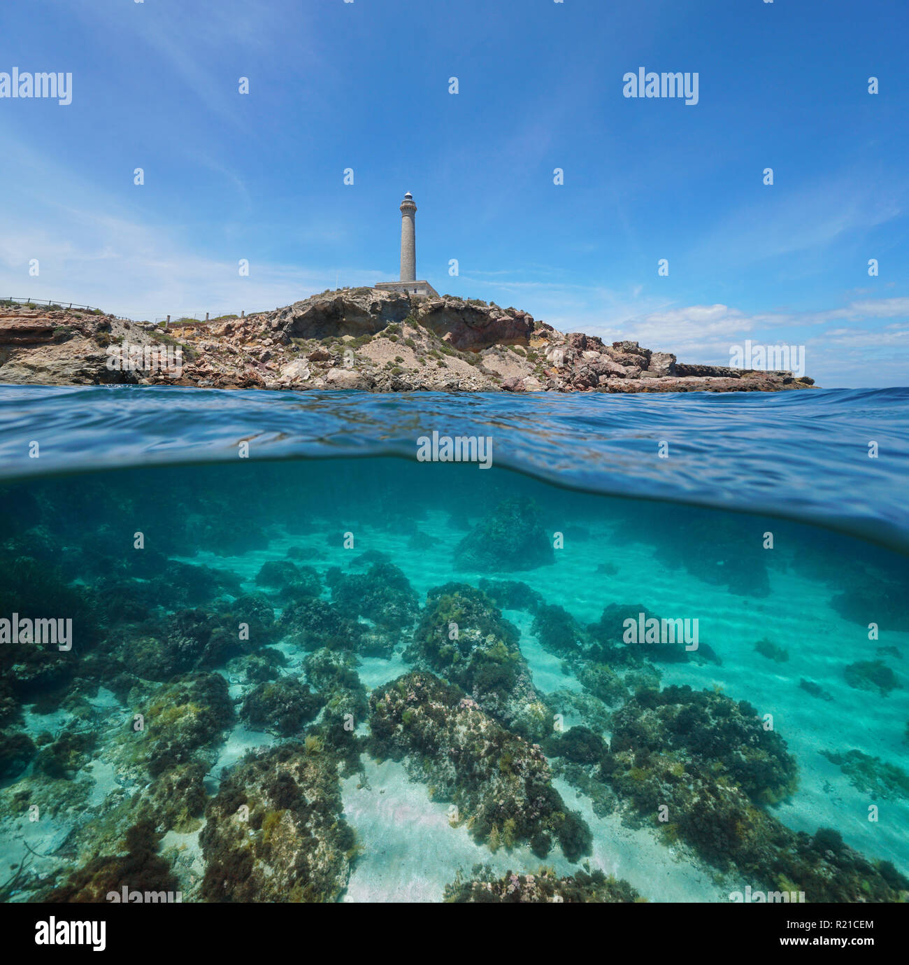 Felsige Küste mit einem Leuchtturm und Felsen mit Sand Unterwasser, geteilte Ansicht Hälfte oberhalb und unterhalb der Oberfläche, Mittelmeer, Cabo de Palos, Spanien Stockfoto