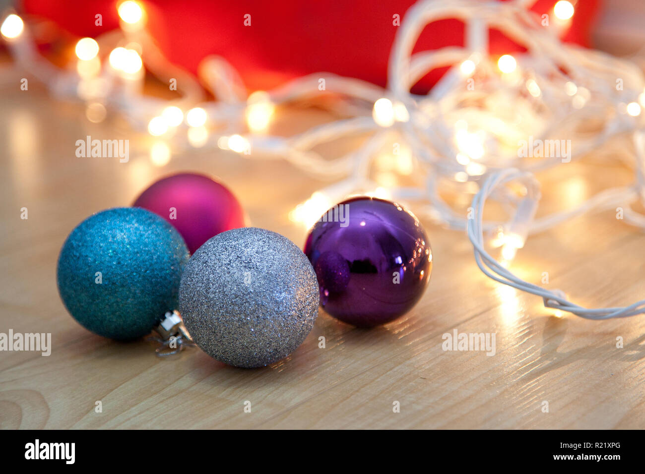 Vier bunte Weihnachtslichter mit Verfilztem weiße Lichter auf dem Boden Stockfoto