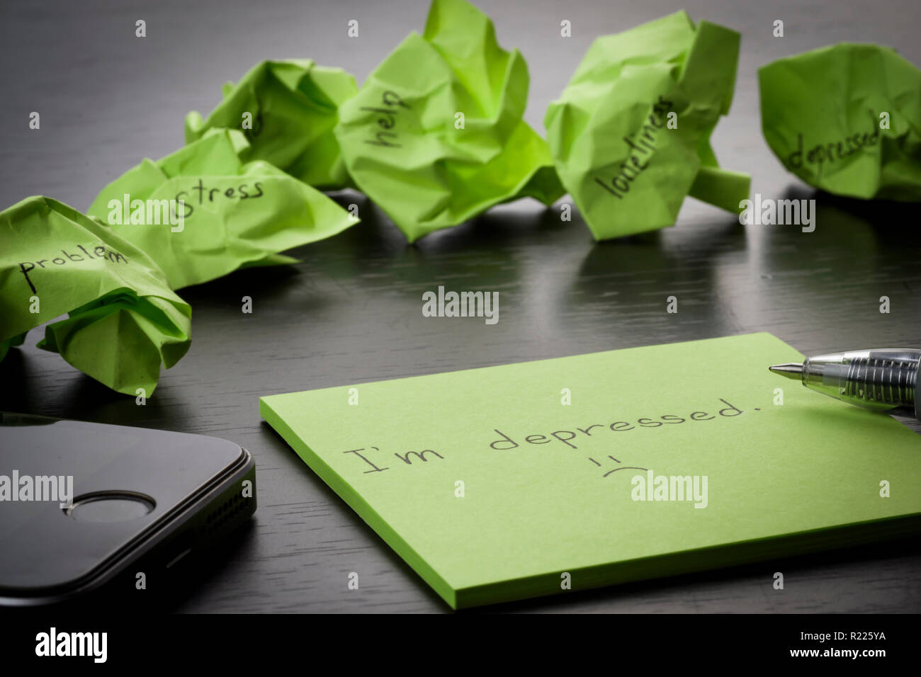 Depression. "Ich depressiv bin" liegt auf einem grünen Zettel auf Holz- schwarz Tabelle geschrieben. Zerknitterte grün Haftnotizen sind verstreut mit Texten. Stockfoto