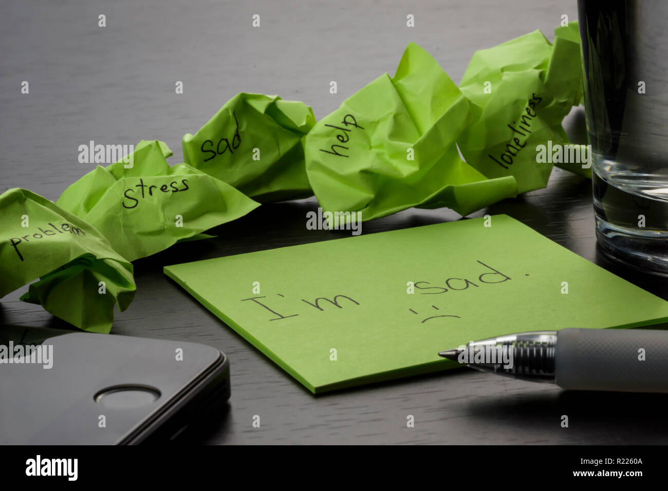 Depression. Die Formulierung ' ' Ich bin Sa'auf einem grünen Zettel auf Holz- schwarz Tabelle geschrieben. Zerknitterte grün Haftnotizen sind verstreut mit Texten. Stockfoto