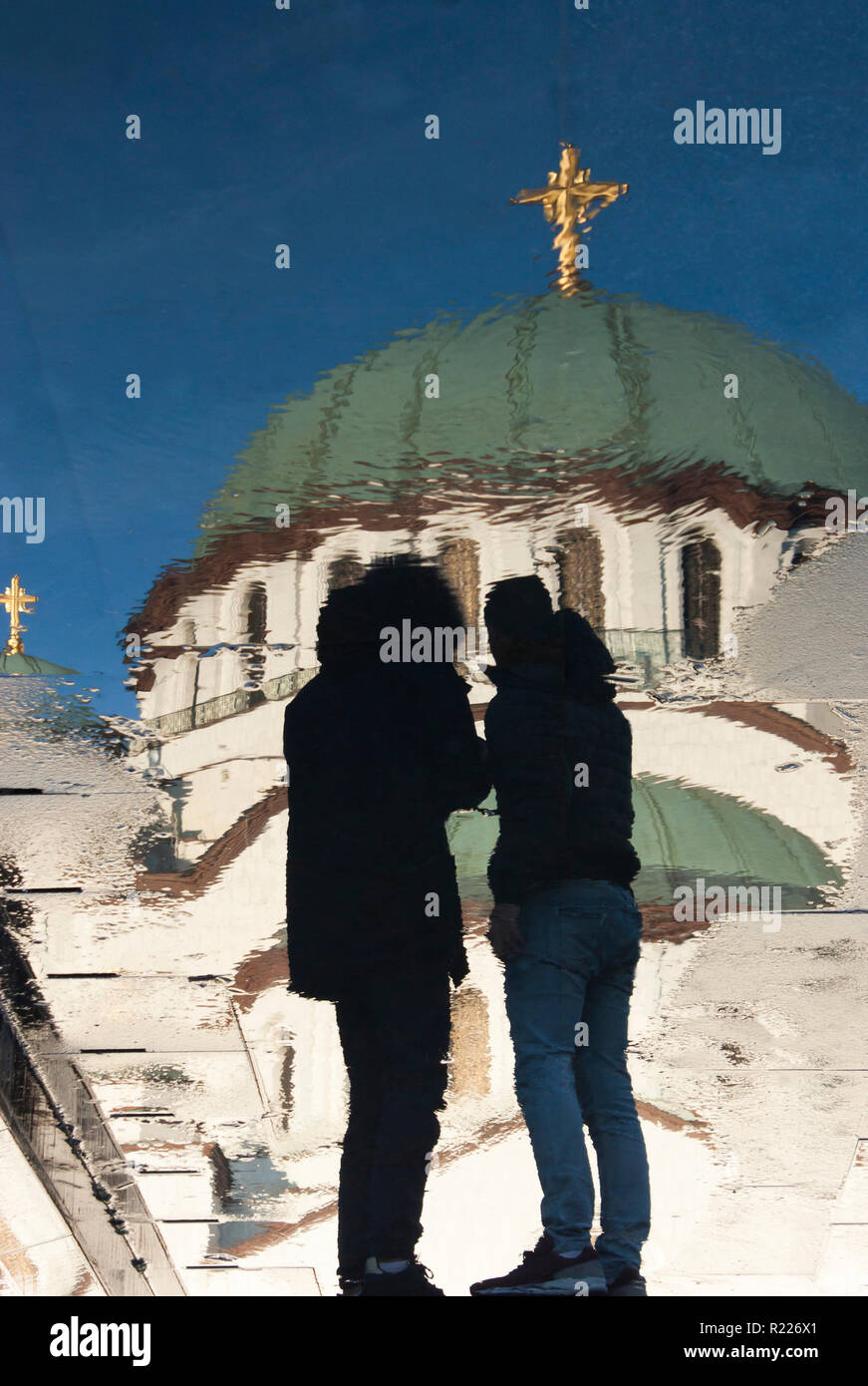 Unscharfe Reflexion des Heiligen Sava orthodoxer Tempel und einige Leute nähern, auf Nasser City Pflaster in Belgrad, Serbien Stockfoto