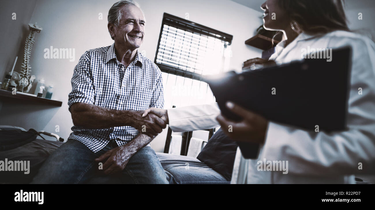 Low Angle View von Therapeuten und ältere männliche Patienten die Hände schütteln Stockfoto