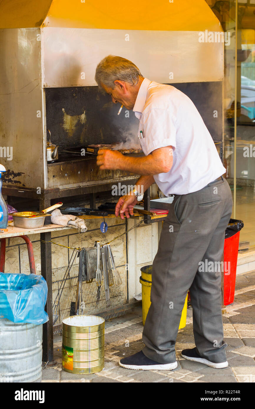 4. Mai 2018. Ein druse arabischer Mann kochen Halal Fleisch auf ein Restaurant Grill mit einem Edelstahl Dunstabzugshaube Schornstein in der Stadt Buqata im Golan H Stockfoto