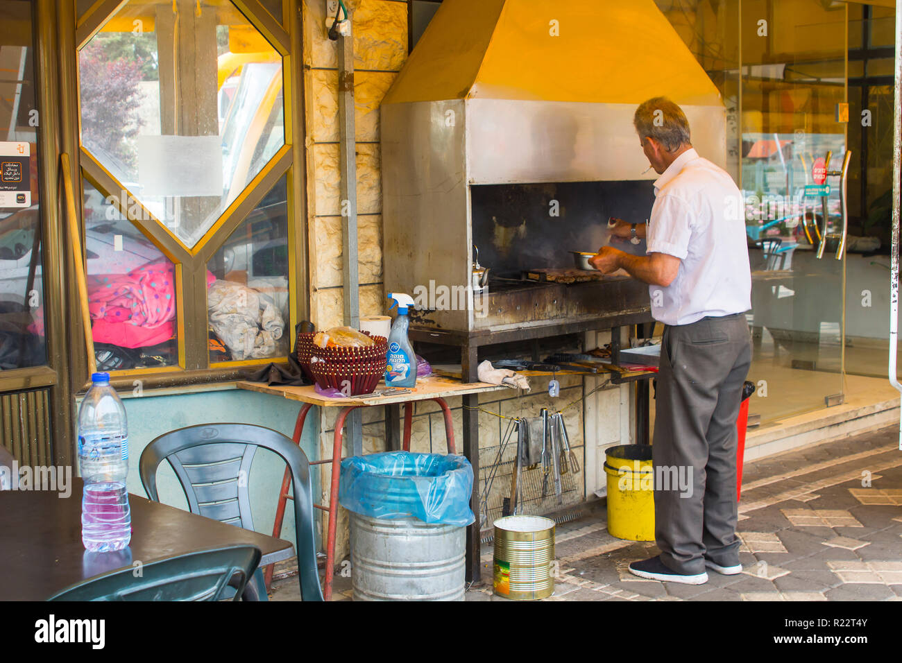 4. Mai 2018. Ein druse arabischer Mann kochen Halal Fleisch auf ein Restaurant Grill mit einem Edelstahl Dunstabzugshaube Schornstein in der Stadt Buqata im Golan H Stockfoto