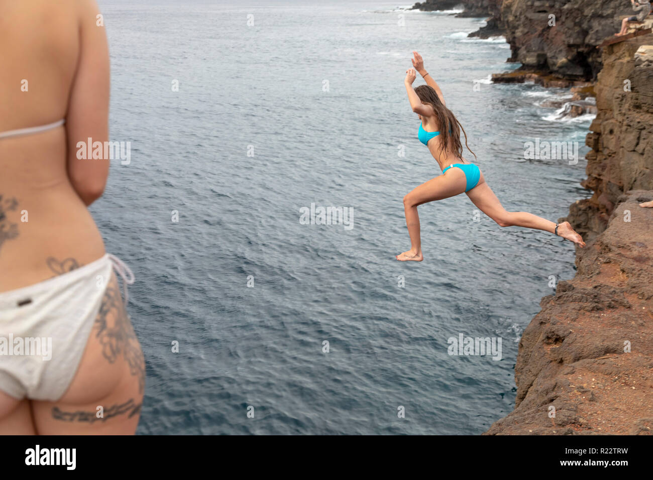 Ka Lae, Hawaii - ein junges Mädchen springt von einer 40-Fuß-Klippe in den Pazifischen Ozean am South Point, der südlichste Punkt in den Vereinigten Staaten, auf Hawa Stockfoto