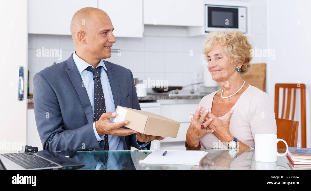 Vertriebsmitarbeiter, Karton mit bestellten Waren ältere Frau in der Küche Stockfoto