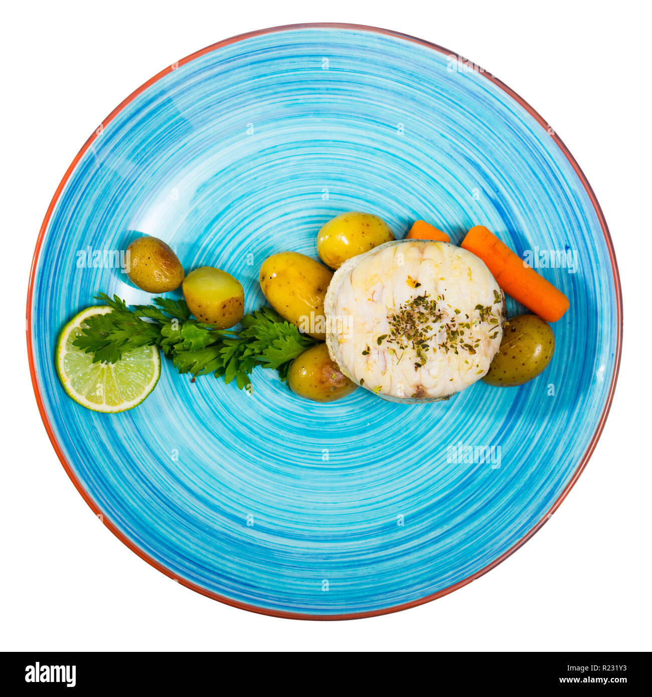 Blick von oben auf die Land Art merluccius serviert auf blaue Platte mit gekochten Kartoffeln, Karotten und Grünen. Auf weissem Hintergrund Stockfoto