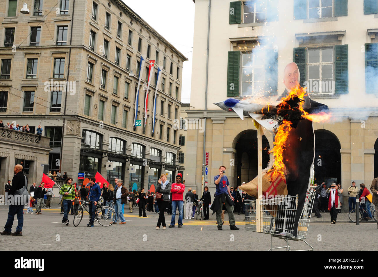 Ein Dummy der Schweizer Bundesrat Ueli Maurer mit einem brennenden militärischen Jet fighter als Protest für das Schweizer Militär Luftfahrt Rüstung Projekt Stockfoto