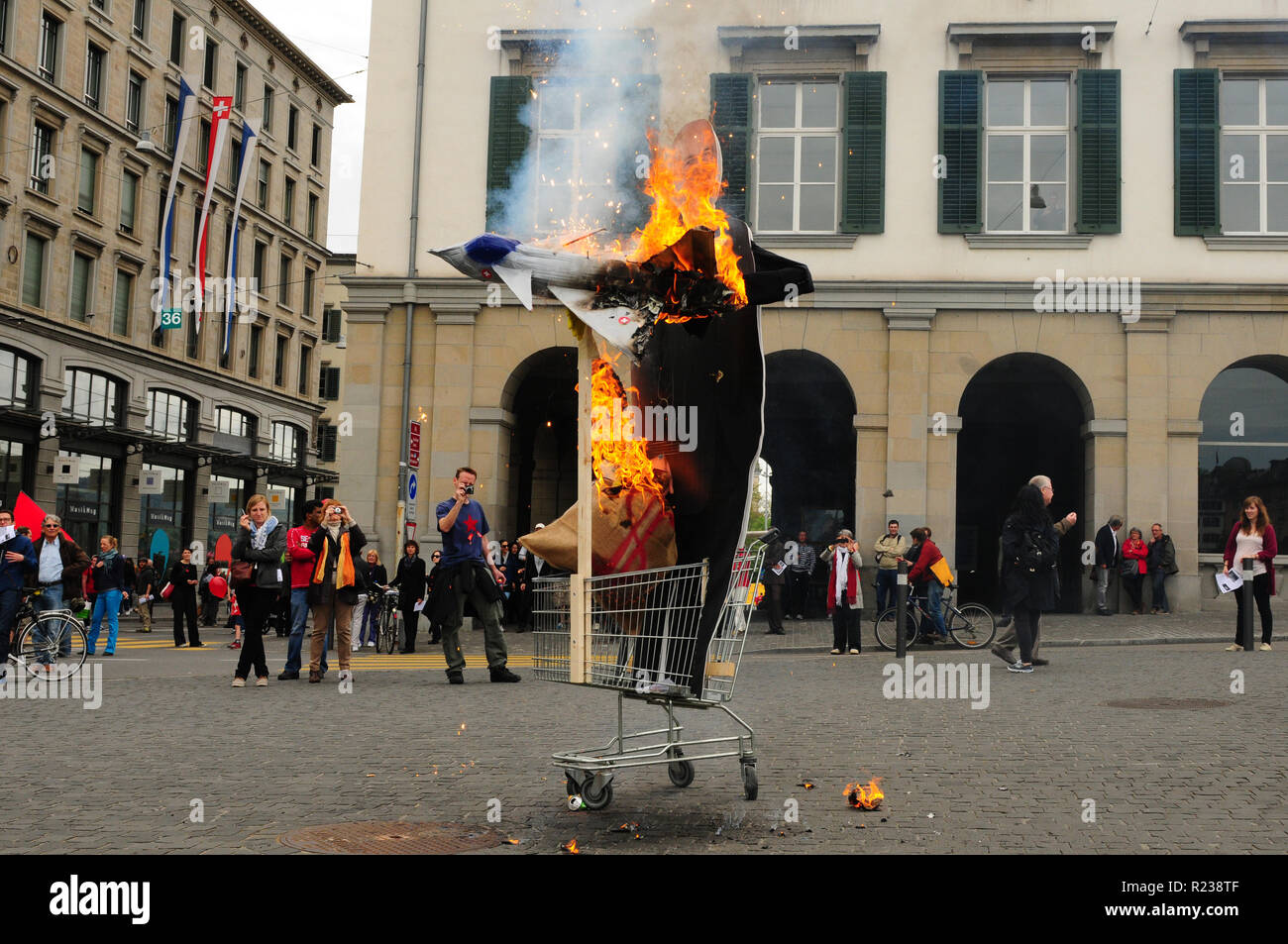 Ein Dummy der Schweizer Bundesrat Ueli Maurer mit einem brennenden militärischen Jet fighter als Protest für das Schweizer Militär Luftfahrt Rüstung Projekt Stockfoto