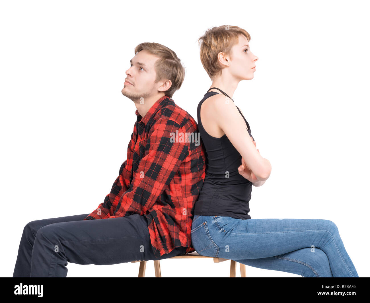 Junges Paar sitzt auf einem Stuhl und auf den verschiedenen Seiten. Auf weiß isoliert. Meinungsverschiedenheiten, Streit, Kommunikation Probleme und Differenzen, Stockfoto