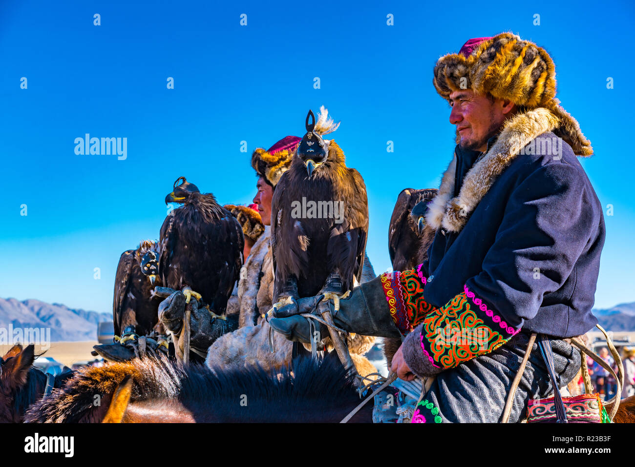 ULGII, Mongolei - OKTOBER 6, 2018: Golden Eagle Festival. Die mongolischen Reiter auf dem Pferd in traditioneller Kleidung mit Adler in der Hand re Stockfoto